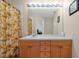 Bright bathroom features vanity with a long countertop, palm tree shower curtain, and a large mirror at 2355 Silver Palm Dr, Kissimmee, FL 34747