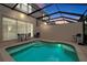 Backyard pool area enclosed, featuring illuminated pool and comfortable seating arrangement at 2355 Silver Palm Dr, Kissimmee, FL 34747
