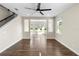 Hardwood flooring in a bright living room, featuring a ceiling fan, stairs, and large windows that provide natural light at 2383 Regency Park Dr, Deland, FL 32724