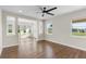 Spacious living room with hardwood floors, a ceiling fan, and bright windows overlooking the backyard at 2383 Regency Park Dr, Deland, FL 32724