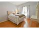 Bright bedroom with a tufted headboard bed, wood floors, and a large window with patterned curtains at 271 W 11Th St, Chuluota, FL 32766