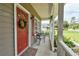 Quaint front porch featuring a decorated door, red shutters, seating, and views of the neighborhood at 271 W 11Th St, Chuluota, FL 32766