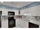 Well-lit kitchen featuring white cabinets, granite countertops, and a tiled backsplash for a modern coastal feel at 33 Sea Haven Dr, Ponce Inlet, FL 32127