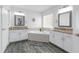 Bright bathroom with granite countertop vanities, tub, grey flooring and natural light at 33215 Kaylee Way, Leesburg, FL 34788