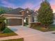 Inviting home featuring a two-car garage, and meticulously maintained landscaping under a colorful sky at 3637 Chandler Estates Dr, Apopka, FL 32712
