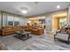 Open-concept living room features stylish wood-look floors, a spacious leather sofa, and plenty of natural light at 3637 Chandler Estates Dr, Apopka, FL 32712