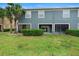 Backyard with green grass and the back of the blue townhouse at 3664 Wilshire Way Rd # 261, Orlando, FL 32829