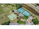 Aerial view of community basketball and tennis courts in a well-maintained neighborhood with plenty of trees at 4718 Magnetite Loop, Mount Dora, FL 32757