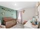 Bedroom with wood crib, green accent wall, and floral decor at 4718 Magnetite Loop, Mount Dora, FL 32757