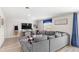 Open living room featuring a large gray sectional, wood floors, and a modern entertainment center at 4718 Magnetite Loop, Mount Dora, FL 32757