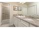 Well-lit bathroom boasting a granite countertop, double sinks, and a glass-enclosed shower at 977 Paradise Dr, Davenport, FL 33897