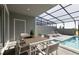 Patio features an outdoor dining table and two sun loungers next to the screened-in pool at 977 Paradise Dr, Davenport, FL 33897