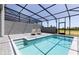 The screened-in pool features sun loungers and steps leading into the sparkling blue water at 977 Paradise Dr, Davenport, FL 33897