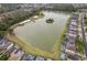 Aerial view highlighting a lake with an island, surrounded by homes, pools, and verdant landscapes at 979 Park Terrace Cir, Kissimmee, FL 34746