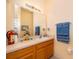 Well-lit bathroom with wooden vanity, neutral countertops, decorative accents, and coordinated blue towels at 979 Park Terrace Cir, Kissimmee, FL 34746