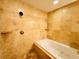 Bright bathroom showcasing a soaking tub with stylish tan tiling throughout and dark fixtures at 101 S Eola Dr # 1209, Orlando, FL 32801
