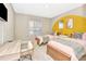Inviting bedroom with a TV, two twin beds, stylish decor and a bright yellow accent wall at 106 Oceans Cir, Daytona Beach, FL 32118