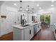 Open kitchen with a large island featuring a sink, modern lighting, white cabinetry, and stainless steel appliances at 1136 W Harvard St, Orlando, FL 32804