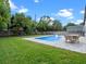 Backyard pool with clear blue water, in-pool lounging chairs, outdoor table, play set and fenced yard at 1136 W Harvard St, Orlando, FL 32804