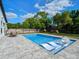 Backyard pool with clear blue water, in-pool lounging chairs, outdoor table, and fenced yard at 1136 W Harvard St, Orlando, FL 32804