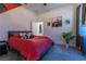 Bright bedroom featuring neutral walls, red bedspread, cowhide pillows, and complementary decorative artwork at 15313 Lebeau Loop, Winter Garden, FL 34787