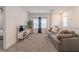 Spacious living area with a gray sofa, carpet flooring, TV, and natural light from the windows at 15313 Lebeau Loop, Winter Garden, FL 34787