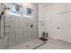 Walk-in shower with gray tile surround, glass partition, and built-in shelving at 15313 Lebeau Loop, Winter Garden, FL 34787