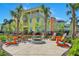 Colorful resort homes surrounding a communal fire pit with Adirondack chairs, set amongst palm trees at 3205 Caribbean Soul Dr, Kissimmee, FL 34747