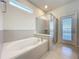 Bright bathroom features a soaking tub and glass-enclosed shower, adjacent to a door with exterior views at 3273 Lilac Way, Davenport, FL 33897