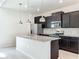 Kitchen island featuring stainless steel appliances, dark cabinets, and pendant lighting at 3273 Lilac Way, Davenport, FL 33897