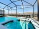 Relax and unwind in this screened-in pool and spa with clear blue water, perfect for hot summer days at 3273 Lilac Way, Davenport, FL 33897