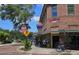 Corner view of brick buildings and storefronts, a bike rack, street signs, and trees under a sunny sky at 383 Floral Dr, Winter Garden, FL 34787