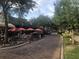 A street with red umbrellas over tables and chairs on a brick road bordered by trees and greenery at 383 Floral Dr, Winter Garden, FL 34787