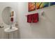 Stylish powder room with pedestal sink, round mirror, and colorful decorative art at 5367 Pinecone Ct, Wildwood, FL 34785