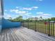 The house has a wooden deck overlooking a large fenced yard under a bright, cloudy sky at 6607 Whispering Pines Rd, Orlando, FL 32824