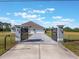 Grand entrance with a paved driveway, black metal gates, and a three-car garage at 6607 Whispering Pines Rd, Orlando, FL 32824