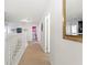 Bright hallway with wood floors, leading to bedrooms and featuring a decorative gold mirror at 8029 Acadia Estates Ct, Kissimmee, FL 34747