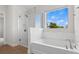 Bright bathroom featuring a soaking tub with a shower and a large window offering a scenic view at 9687 Lost Creek Dr, Winter Garden, FL 34787