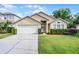 Charming single-story home featuring a well-manicured lawn, two-car garage, and inviting front entrance with arched window at 150 Golfside Cir, Sanford, FL 32773