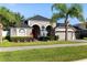A gray single-story home with a well-manicured lawn and a two-car garage, complimented by lush landscaping at 10827 Lemay Dr, Clermont, FL 34711
