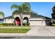 Charming single-story home with a well-manicured lawn and a two-car garage. Has a bright red front door and palm tree at 10827 Lemay Dr, Clermont, FL 34711