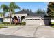 A gray single-story home with a well-manicured lawn and a two-car garage with a long drive way at 10827 Lemay Dr, Clermont, FL 34711