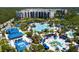 Aerial view of a beautiful resort featuring multiple pools, palm trees, and blue cabanas at 14501 Grove Resort Ave # 3222, Winter Garden, FL 34787