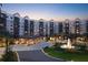 A luxurious multi-story building with a covered entrance, a water fountain, and elegant landscaping at twilight at 14501 Grove Resort Ave # 3222, Winter Garden, FL 34787