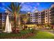 A stunning multi-story building with a water fountain and elegant landscaping at twilight at 14501 Grove Resort Ave # 3222, Winter Garden, FL 34787