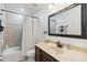 Standard bathroom with a shower-tub combo, dark vanity, and framed mirror at 9826 Heron Pointe Dr, Orlando, FL 32832