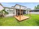 Lush green backyard with wooden pergola and outdoor kitchen, plus the home's screened-in back porch at 1638 Swallowtail Ln, Sanford, FL 32771