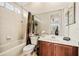 Bright bathroom features tile surround shower and tub combo, wooden vanity with large mirror, and a view into the hall at 1638 Swallowtail Ln, Sanford, FL 32771