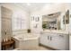 Bright bathroom featuring soaking tub with tile surround, shutters, and double vanity at 1638 Swallowtail Ln, Sanford, FL 32771