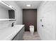 Modern bathroom featuring stylish vanity with backlit mirror, sleek toilet, and a textured accent wall at 305 Sweetwater Club Cir, Longwood, FL 32779